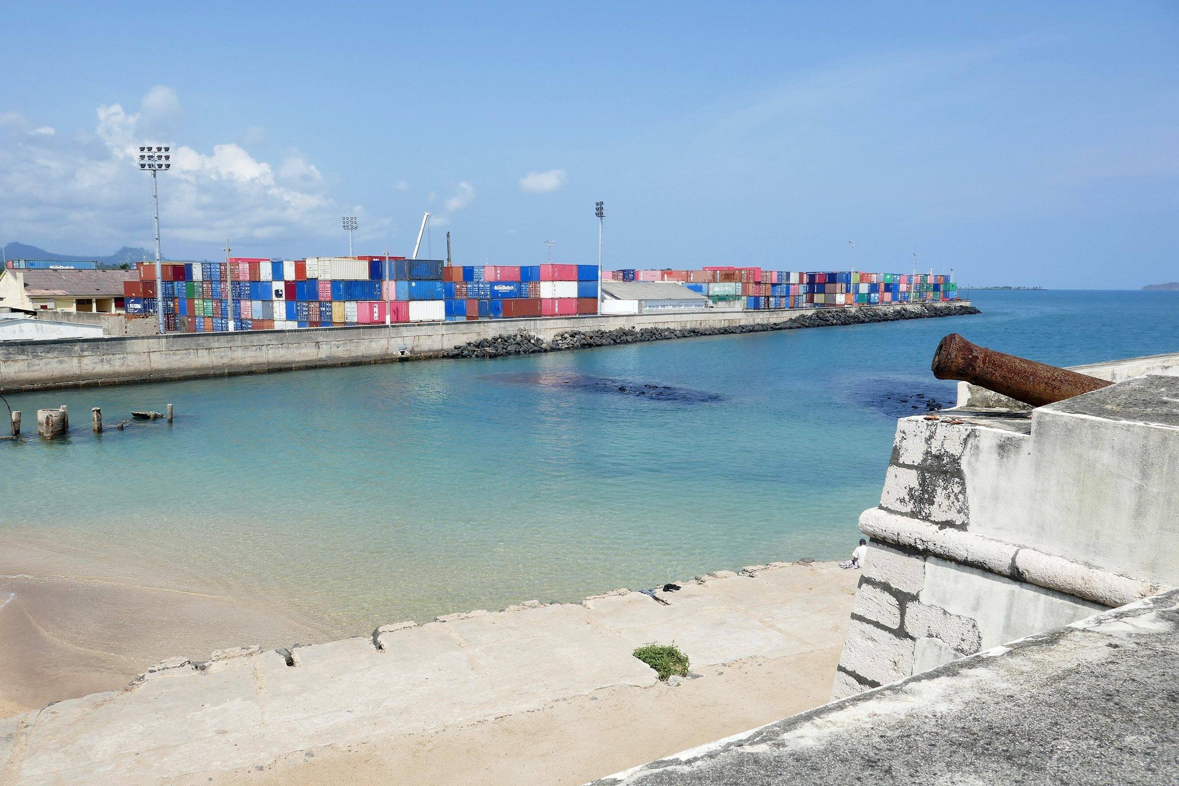 A cannon on the walls of Fort São Sebastião above a sandy cove