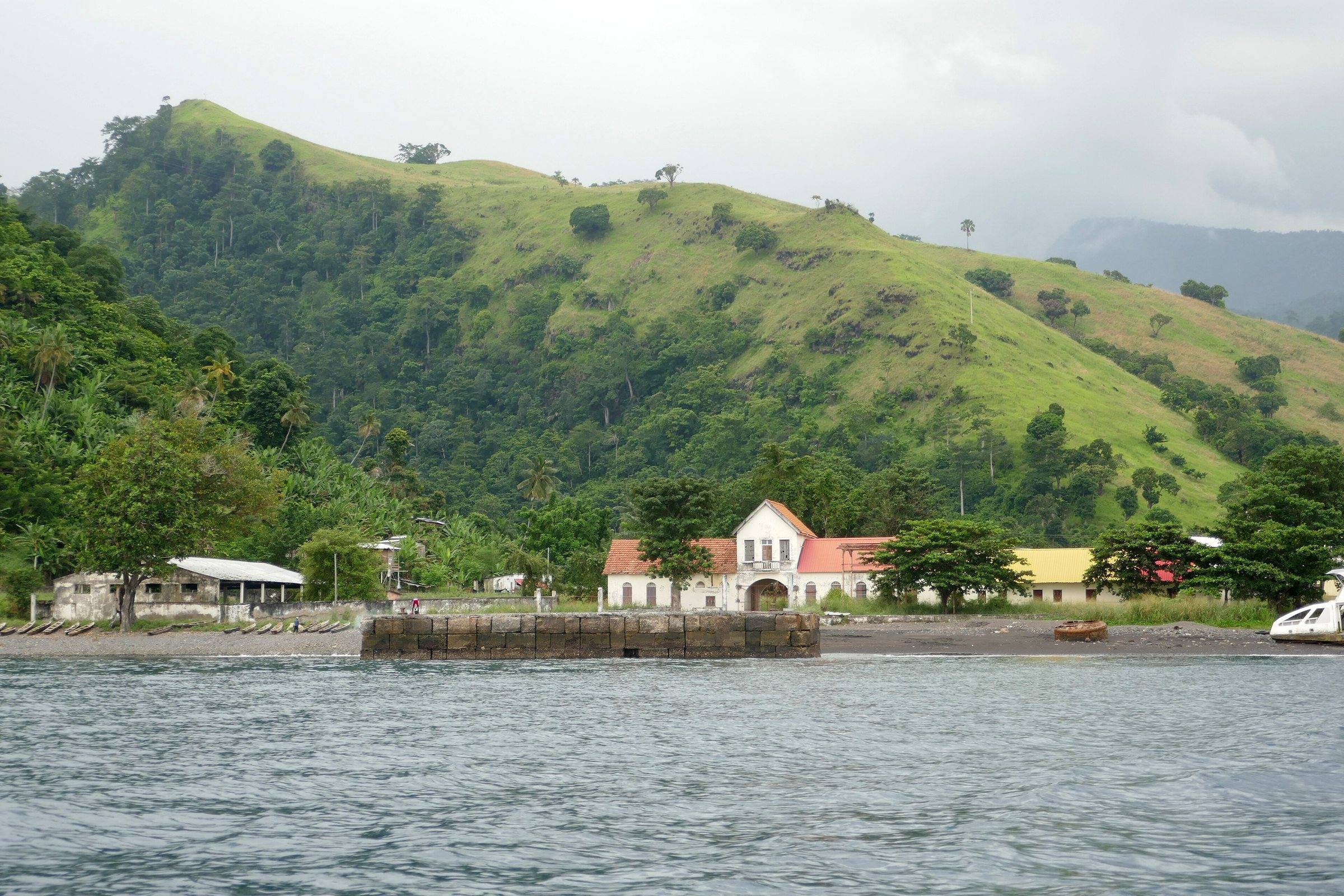 Colonial buildings along the waterfront at Neves below green hills